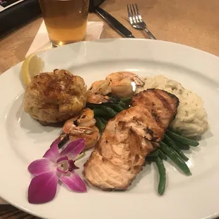 Seafood platter with crab cake, shrimp, salmon, mashed potatoes, and green beans