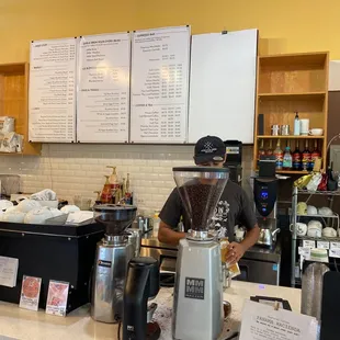 a man standing behind the counter of a coffee shop