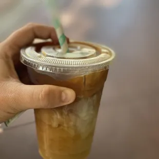 a hand holding a cup of iced coffee