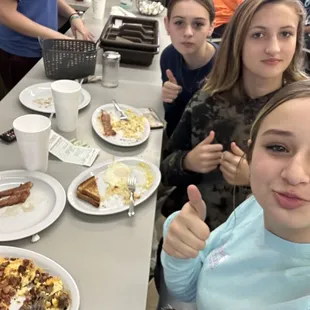 a group of people sitting at a table with plates of food
