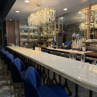 a bar with blue chairs and a chandelier