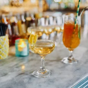 two glasses of alcohol and a pitcher of lemonade