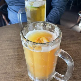 a glass of orange juice and a mug of beer