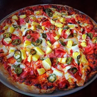 a pizza with pineapples, peppers, and jalapenos