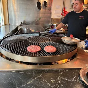 a man cooking hamburgers on a grill