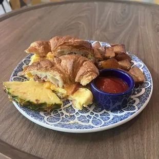 a croissant sandwich on a plate with a side of ketchup