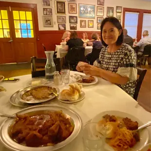 a woman sitting at a table with plates of food