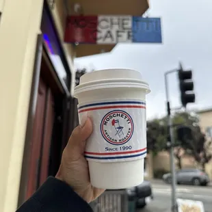 a hand holding a coffee cup
