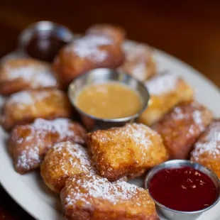 a plate of doughnuts with dipping sauce