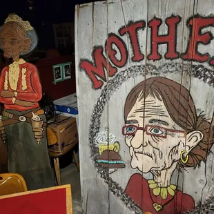 a woman with glasses standing next to a wooden sign