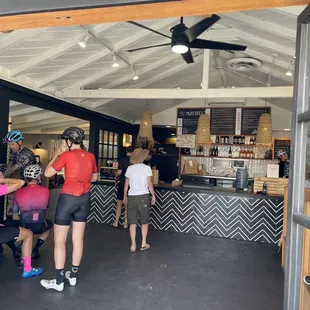 Some cyclists are lining up for grub. Next door is a cycle shop.