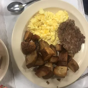 Breakfast plate eggs, pork sausage, potatoes and two large biscuits.