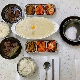 Abalone porridge with egg, jangjorim (soy braised beef), pickled radish, radish kimchi, and cabbage kimchi. Dipping salt is for gamgyetang.