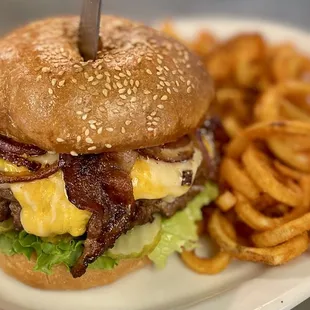 a burger with bacon, cheese, lettuce, and onion rings