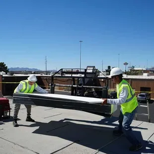 two men in safety vests working on a roof