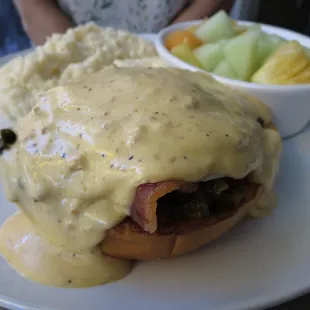 Mozelle's Benedict - candied bacon, spicy collards, chorizo gravy, fried egg on brioche bun. Cheese grits and fresh fruit.