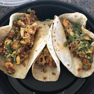 three tacos on a black plate
