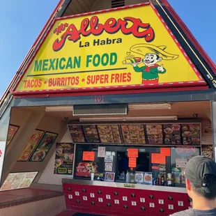 a man standing in front of a mexican food stand