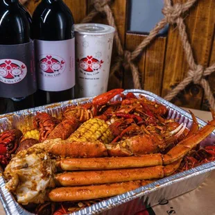 crab legs, corn, corn on the cob, and two bottles of wine