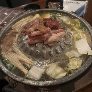 Mookata grill with napa cabbage, enoki mushrooms, Minced pork, and different meat cuts.