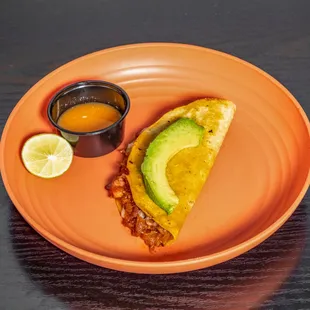 an orange plate with a slice of avocado on it
