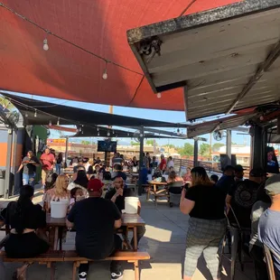 a large group of people sitting at tables under a canopy