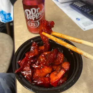 a bowl of chicken with chopsticks