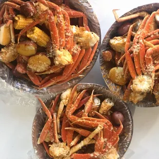 three bowls of crab legs and potatoes