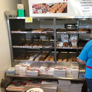 a woman standing in front of a display of donuts