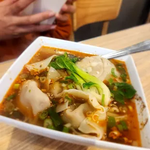  a person taking a picture of a bowl of soup
