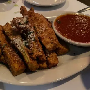 a plate of french fries and a bowl of tomato sauce
