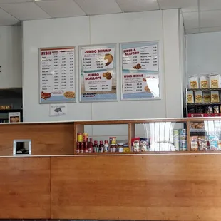 a restaurant counter with a menu on the wall