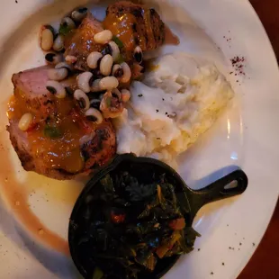 Pork loin with mashed potatoes and collard greens.