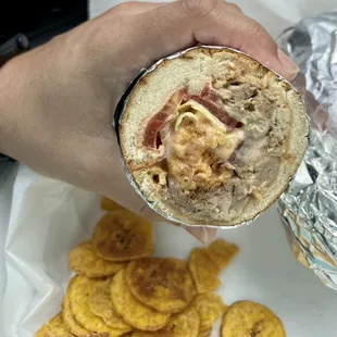 Tripleta sandwich: soft bread, pulled pork, lettuce, tomato, potato sticks with mayo-ketchup, plantain chips as a side.