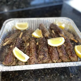 a tray of meat with lemon slices