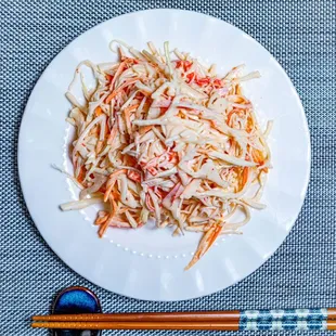  a plate of shredded carrots with chopsticks