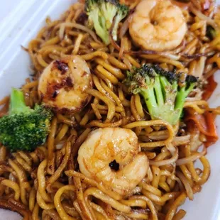 a plate of noodles with shrimp and broccoli