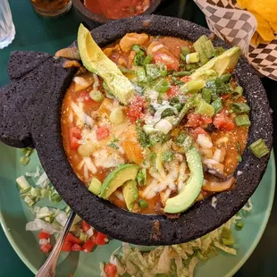 A hot large pig-shaped bowl filled with chicken, beef, and  (optional) shrimp mixed as a tasty stew..