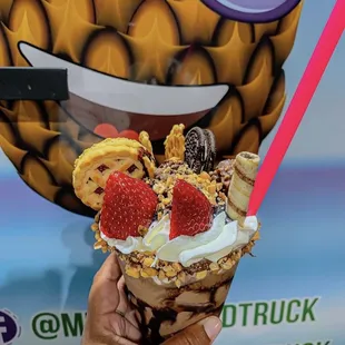 a hand holding a large ice cream sundae