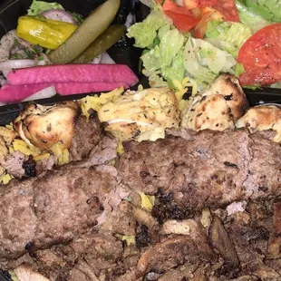 Combo plate with Chicken Shish Kabab and Beef Shawarma served on dill/yellow rice. With side salad and pickled vegetables