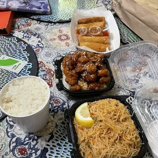 Orange chicken, pancit, lumpia mix, and white rice.