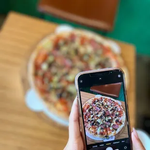 a person taking a picture of a pizza