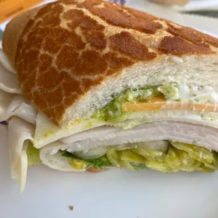 Customized turkey sandwich: Dutch crunch roll with lettuce, pickles, peppers, cheddar cheese, Mayo, mustard, and garlic sauce.