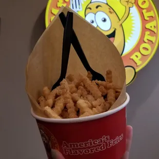 a hand holding a cup of fried food