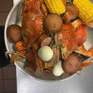 a bowl of crab, potatoes, corn, and potatoes