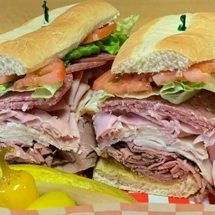 a large sandwich with meat, lettuce, tomatoes, and pickles