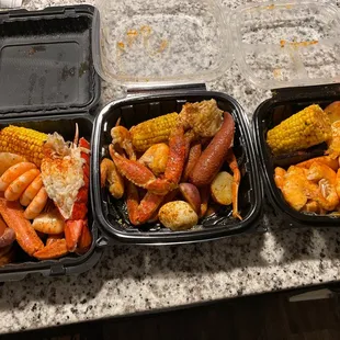 three containers of shrimp, corn, and potatoes