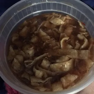 a person holding a plastic bowl of soup