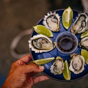 a person holding a plate of oysters