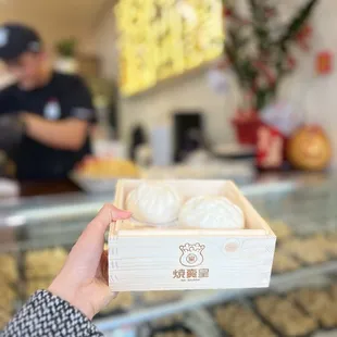 a person holding a box of dumplings